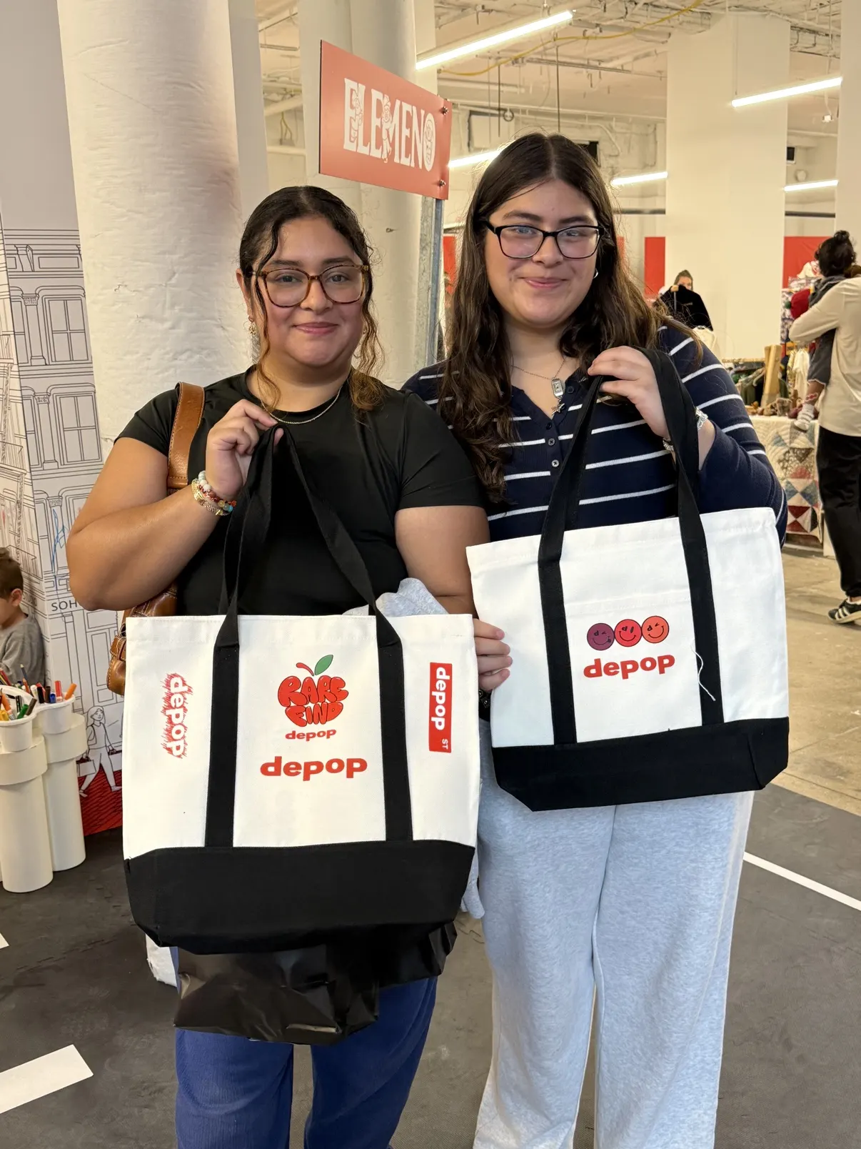 Two guests at a Depop event holding the totes they had customized