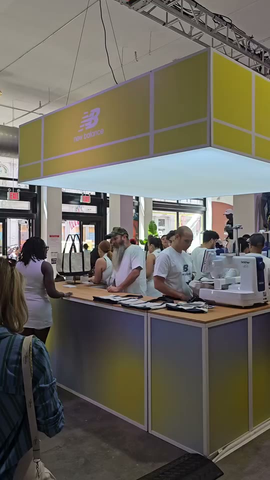 The crew running embroidery machines at the New Balance activation booth while guests line up at the counter