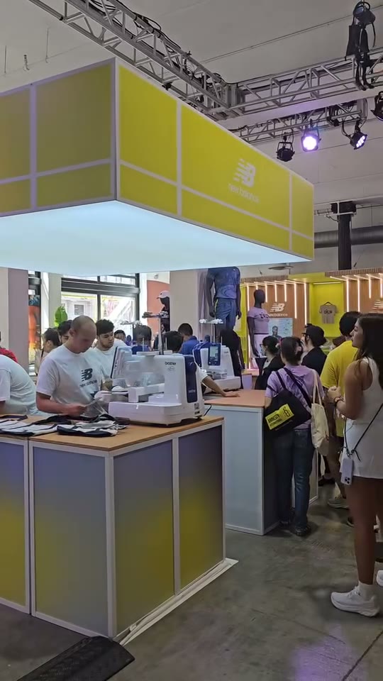 Embroidery machines working the New Balance activation booth with a crowd of guests waiting
