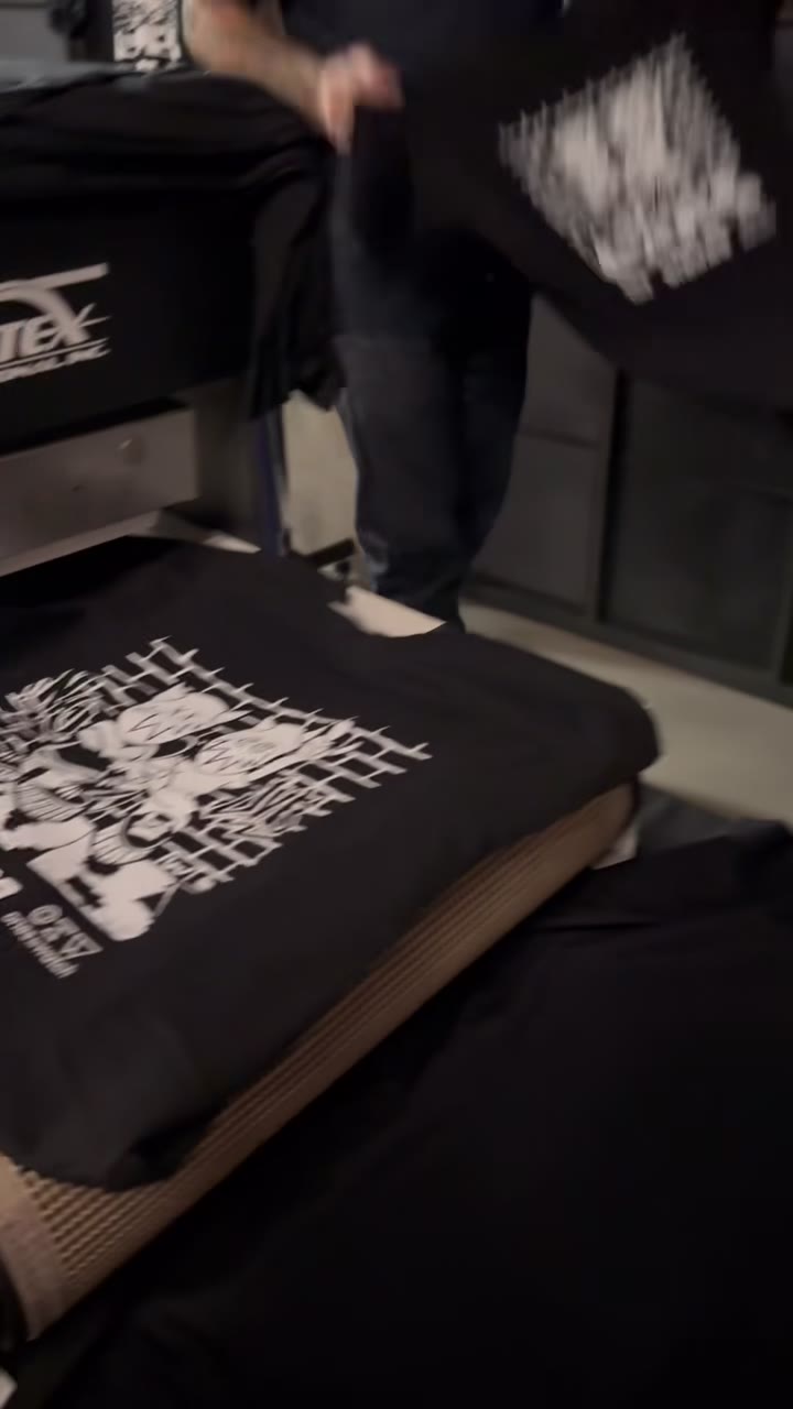 Black event tees with white graphics coming off the dryer at an indoor activation