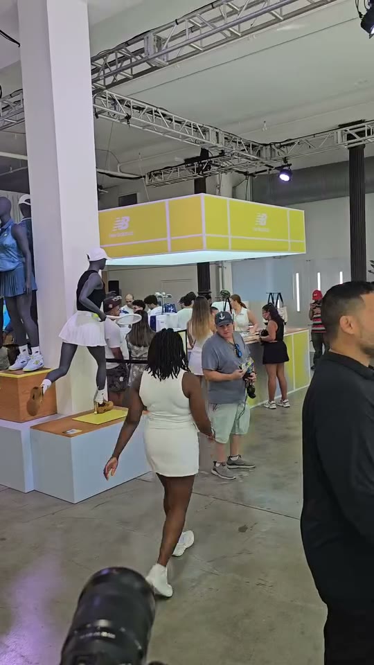 Wide view of the New Balance pop-up floor — guests moving between the mannequins in tennis kits and the embroidery counter