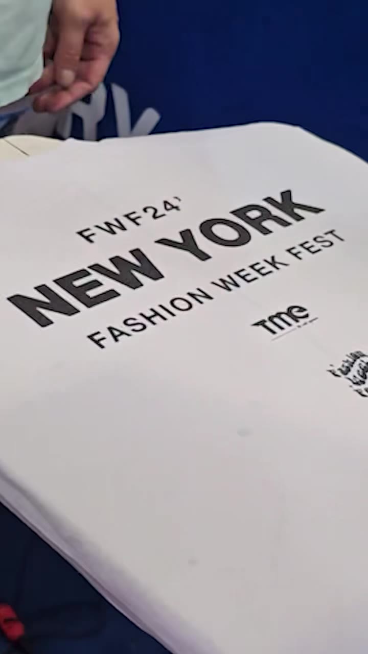A white tote printed FWF24 — New York Fashion Week Fest, held up close