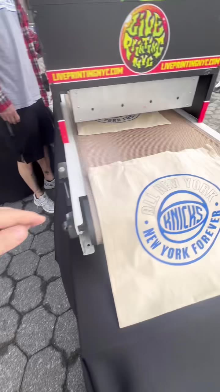 A fresh Knicks tote — All New York, New York Forever — coming through their Live Printing NYC-branded dryer at the pier setup