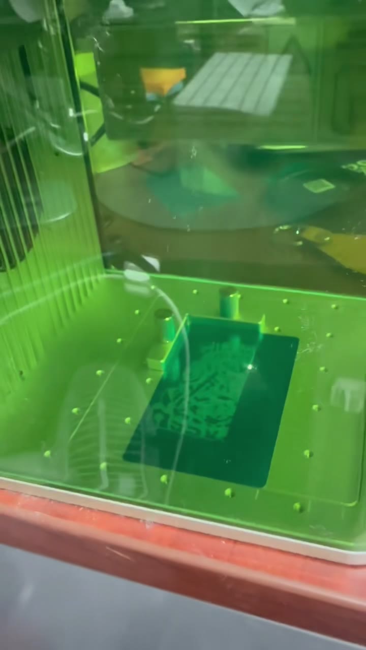 An intricate design forming on a card under the laser's green lid