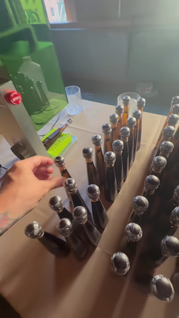 A production table covered with rows of engraved bottles, dozens deep, the laser at the end of the table
