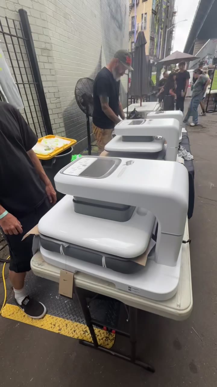 A row of auto heat presses working the event line, green Nike jerseys stacked and ready