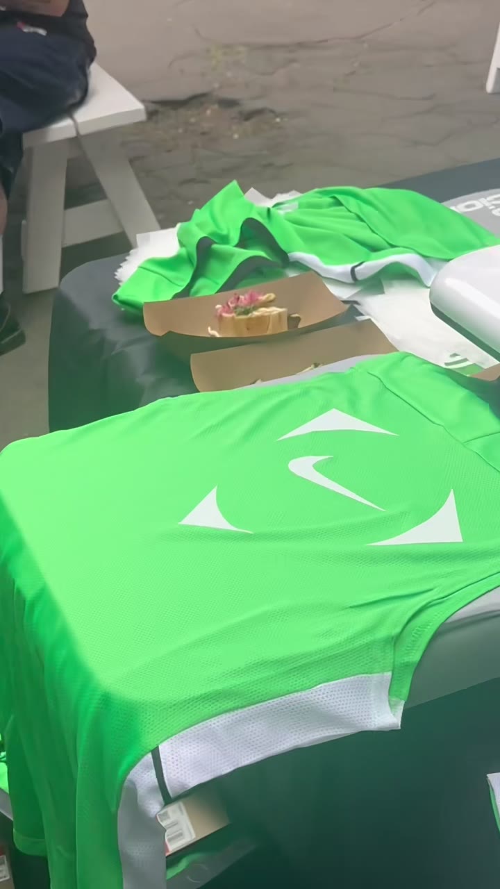 A finished green Nike jersey laid out with the white mark pressed on