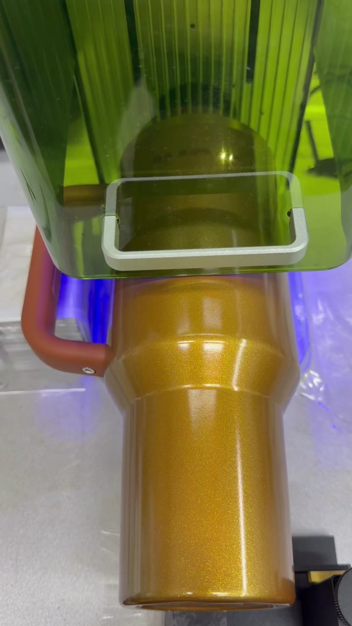 A gold glitter tumbler under the laser hood, mid-engrave